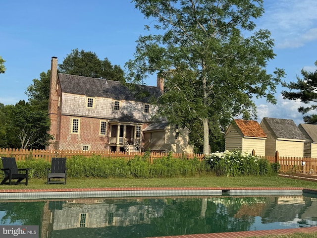 rear view of property featuring a lawn and a fenced in pool