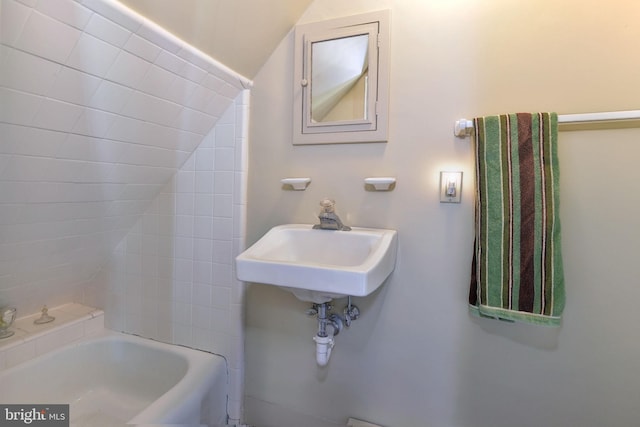 bathroom featuring lofted ceiling and a bath