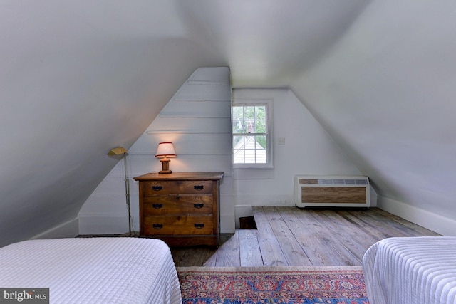 bedroom featuring hardwood / wood-style floors, lofted ceiling, and heating unit