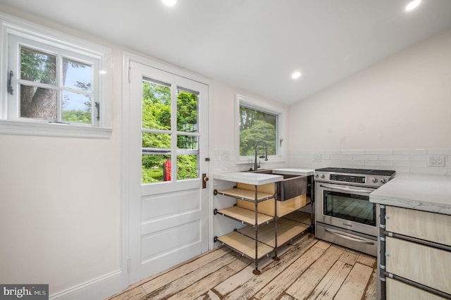 kitchen featuring decorative backsplash, light hardwood / wood-style floors, sink, and stainless steel range