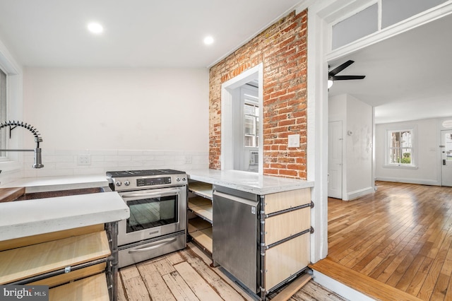 kitchen featuring ceiling fan, light hardwood / wood-style flooring, stainless steel range oven, and sink