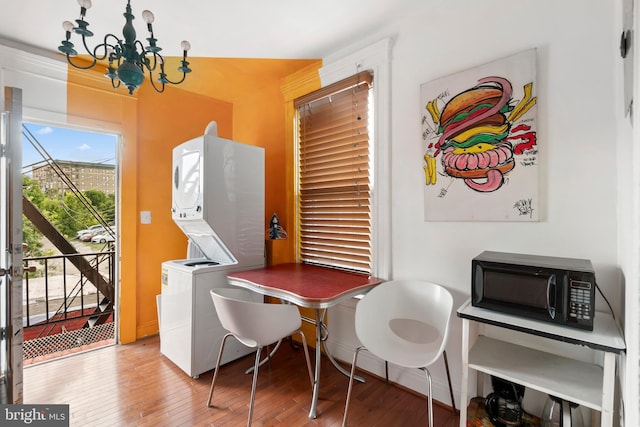 dining room with a chandelier, hardwood / wood-style floors, and stacked washer / drying machine