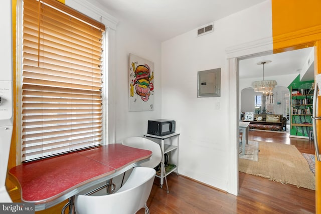 dining room featuring electric panel, hardwood / wood-style flooring, and an inviting chandelier