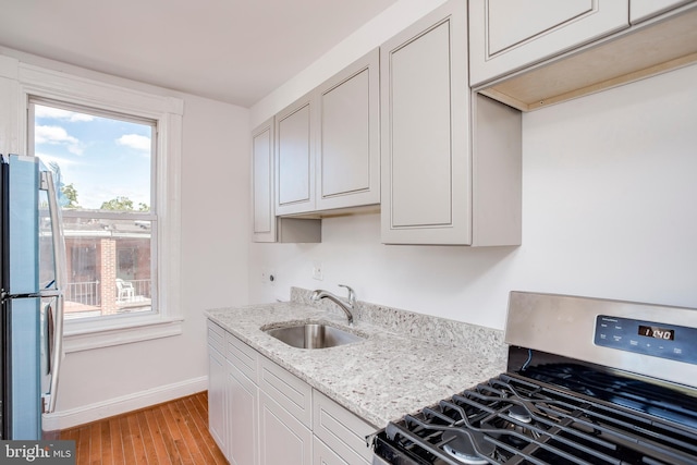 kitchen featuring light stone counters, sink, light wood-type flooring, and stainless steel appliances