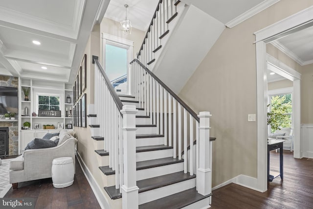 staircase featuring hardwood / wood-style flooring, ornamental molding, a fireplace, and an inviting chandelier