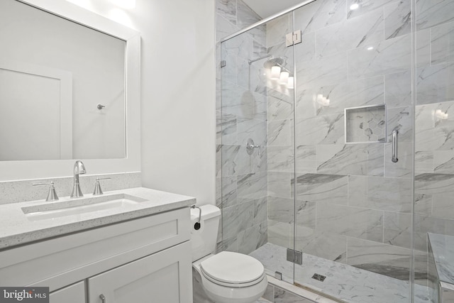 bathroom featuring vanity, a shower with door, and toilet