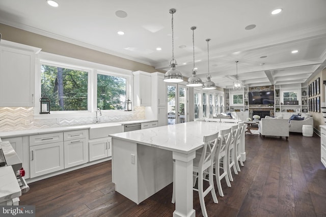 kitchen with white cabinetry, decorative light fixtures, light stone countertops, and a kitchen island