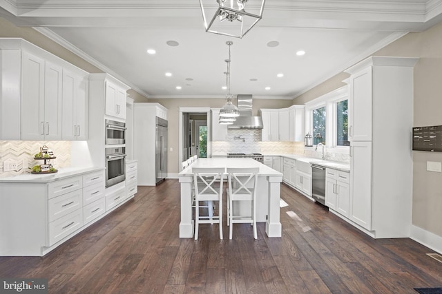 kitchen featuring wall chimney exhaust hood, white cabinetry, a center island, a wealth of natural light, and stainless steel appliances