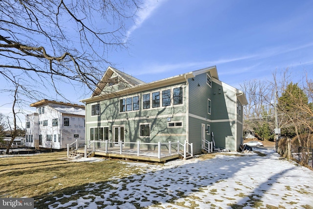 snow covered back of property with a deck