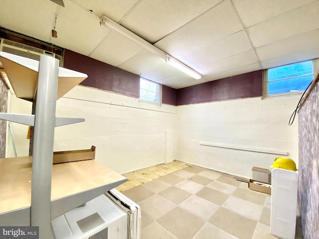 basement featuring a paneled ceiling and light wood-type flooring