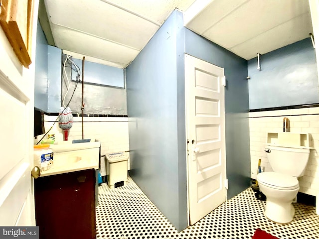 bathroom featuring tile walls, toilet, and vanity