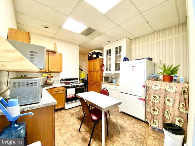 kitchen featuring white appliances, white cabinetry, light tile floors, and a drop ceiling