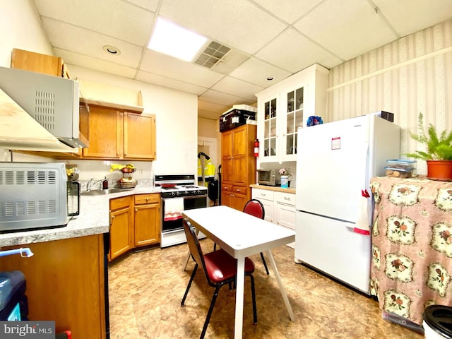 kitchen featuring sink, white appliances, light tile floors, and a drop ceiling