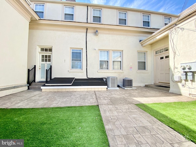 rear view of house with a patio area, central air condition unit, and a yard