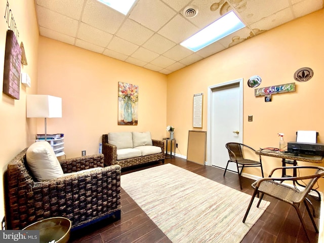 living room with dark hardwood / wood-style floors and a drop ceiling