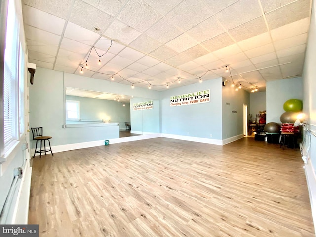 interior space with a drop ceiling, track lighting, and wood-type flooring