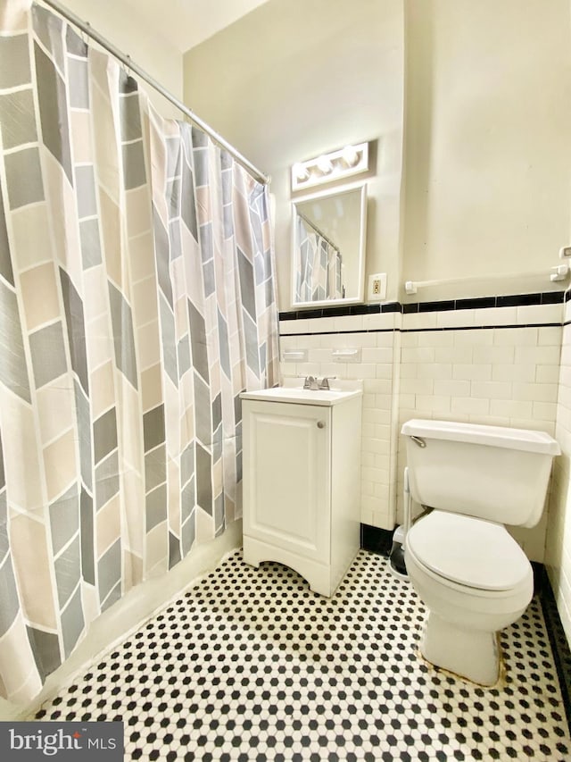 bathroom with vanity, toilet, and tile walls