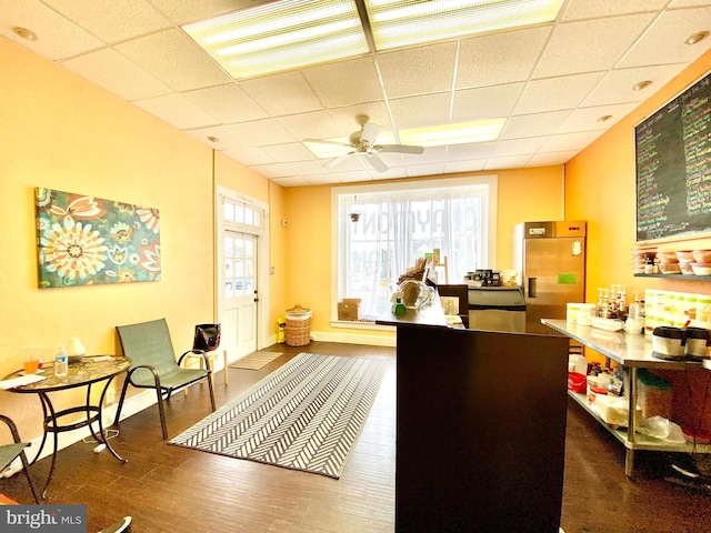 office space with dark wood-type flooring, ceiling fan, and a drop ceiling