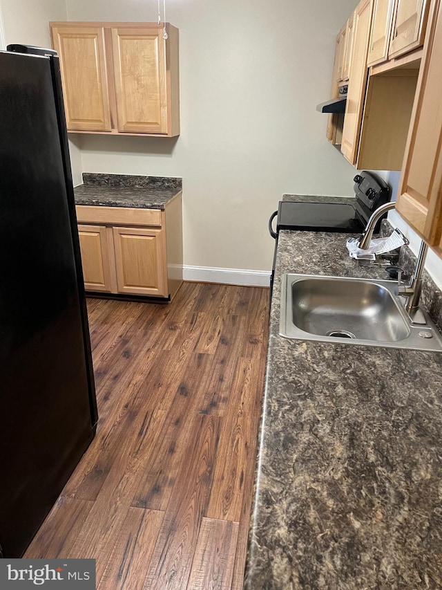 kitchen with black refrigerator, sink, dark hardwood / wood-style floors, light brown cabinetry, and range