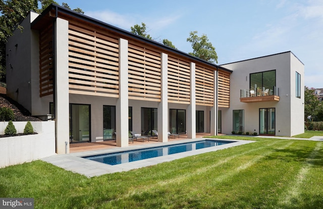 back of property featuring a balcony and a lawn