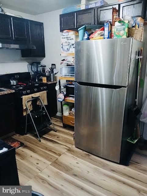 7304 Malden Ln, District Heights, MD 20747 - kitchen featuring freestanding refrigerator, range with gas cooktop, light wood finished floors, dark cabinetry, and under cabinet range hood