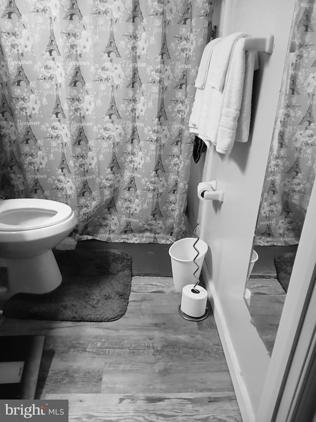 bathroom with curtained shower, toilet, and wood-type flooring