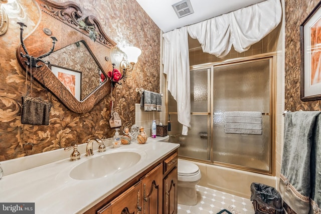 full bathroom featuring shower / bath combination with glass door, tile patterned floors, vanity, and toilet