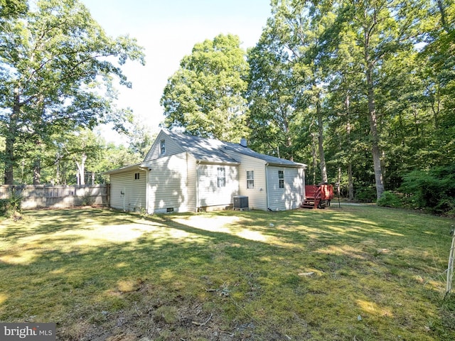 rear view of property with central air condition unit and a lawn