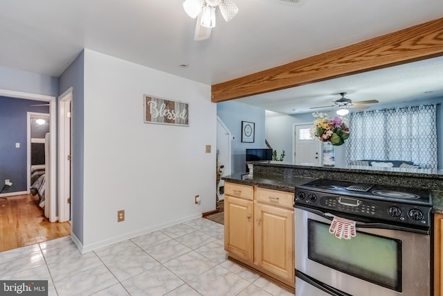 kitchen with light brown cabinetry, dark stone counters, ceiling fan, beam ceiling, and stainless steel stove