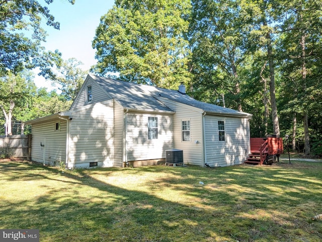 rear view of property with a lawn, cooling unit, and a deck