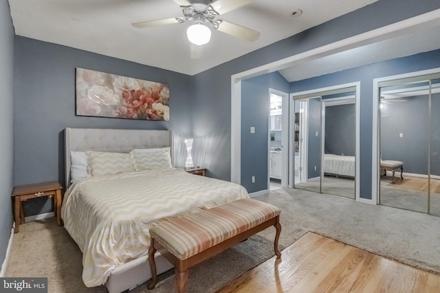 bedroom with hardwood / wood-style flooring, ceiling fan, and multiple closets