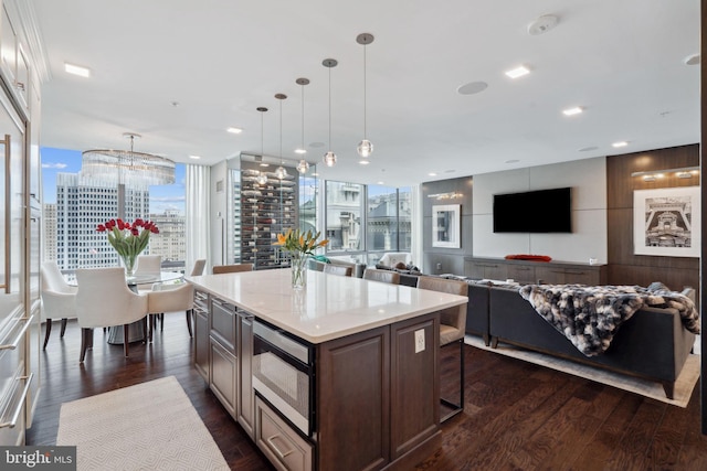 kitchen featuring stainless steel microwave, a center island, a kitchen breakfast bar, dark hardwood / wood-style flooring, and decorative light fixtures