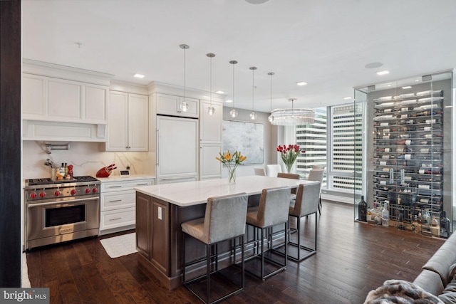 kitchen with a center island, high quality appliances, hanging light fixtures, dark hardwood / wood-style flooring, and white cabinetry