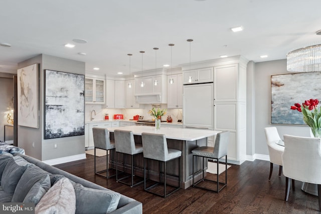 kitchen featuring dark hardwood / wood-style flooring, a breakfast bar, a kitchen island, decorative light fixtures, and white cabinetry