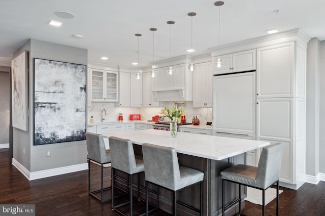 kitchen featuring white cabinets, pendant lighting, a kitchen bar, and dark hardwood / wood-style floors