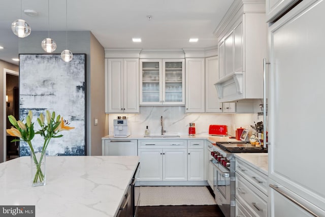 kitchen featuring white cabinetry, sink, decorative light fixtures, and high end appliances