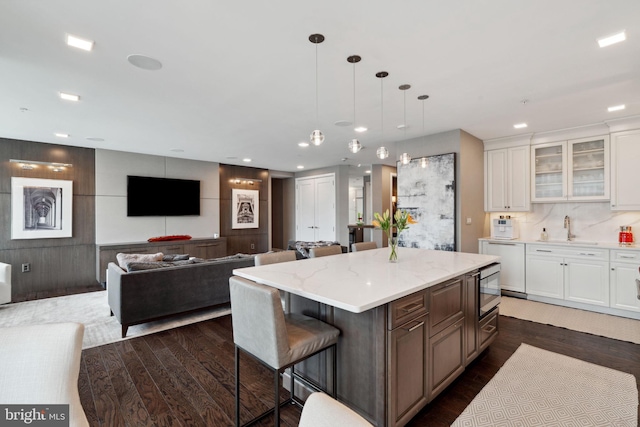 kitchen featuring white cabinetry, sink, a kitchen breakfast bar, dark hardwood / wood-style flooring, and a kitchen island