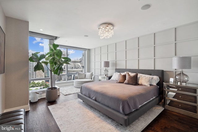 bedroom featuring a wall of windows, dark wood-type flooring, and an inviting chandelier