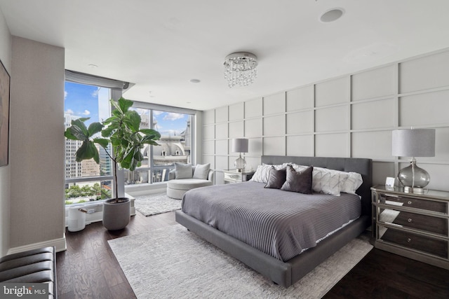 bedroom with a wall of windows, a chandelier, and hardwood / wood-style flooring