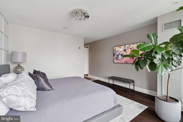 bedroom featuring a chandelier and dark wood-type flooring