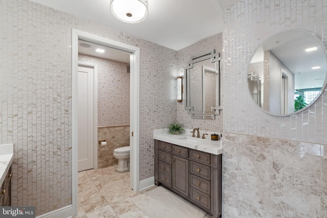 bathroom featuring vanity, tile walls, and toilet