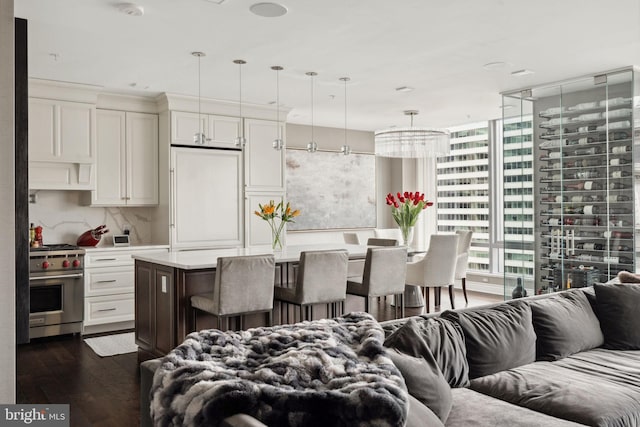 kitchen featuring a kitchen island, high end appliances, dark wood-type flooring, pendant lighting, and white cabinetry