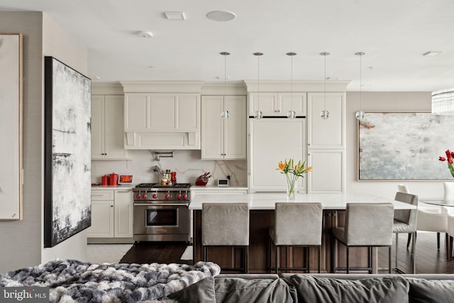 kitchen with white refrigerator, premium range hood, premium stove, decorative light fixtures, and a breakfast bar area