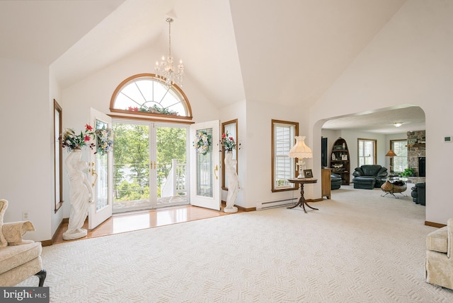 carpeted entryway featuring a notable chandelier, a fireplace, baseboard heating, and high vaulted ceiling