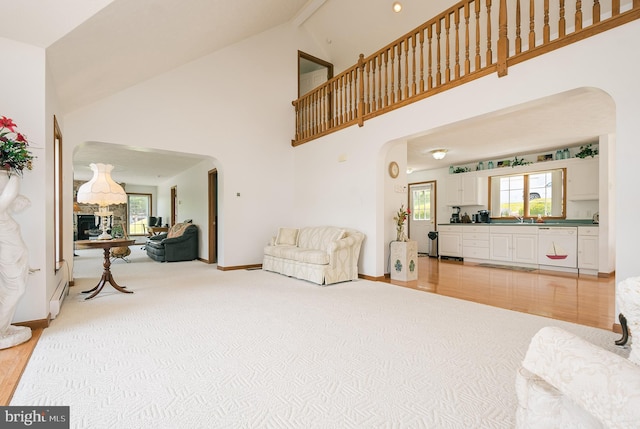 carpeted living room featuring beam ceiling, high vaulted ceiling, and a baseboard heating unit