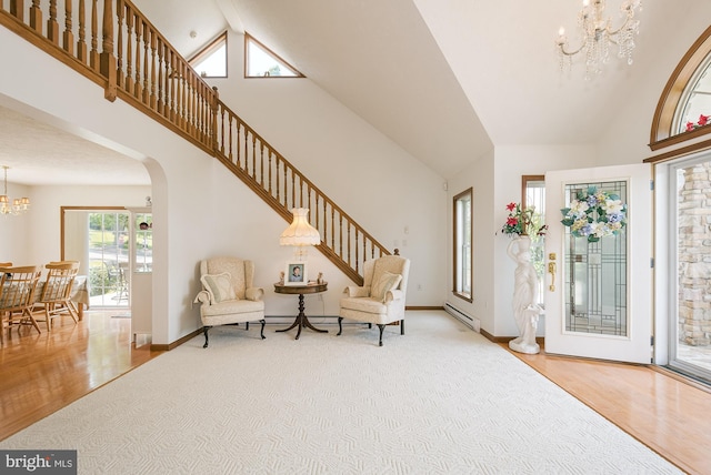 entrance foyer with hardwood / wood-style flooring, an inviting chandelier, high vaulted ceiling, and a baseboard heating unit