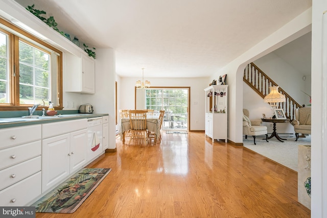 kitchen with white dishwasher, sink, pendant lighting, white cabinetry, and plenty of natural light