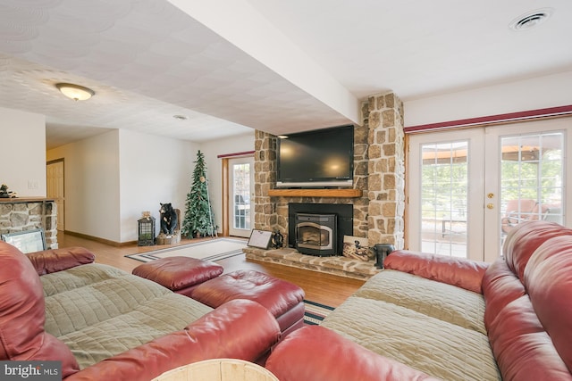 living room with a fireplace, french doors, and light hardwood / wood-style flooring