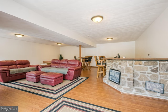 living room with hardwood / wood-style floors, a stone fireplace, a textured ceiling, and indoor bar