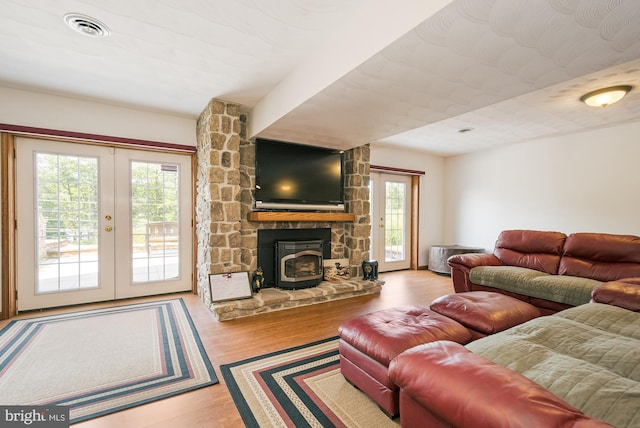 living room with light wood-type flooring, french doors, and a wood stove